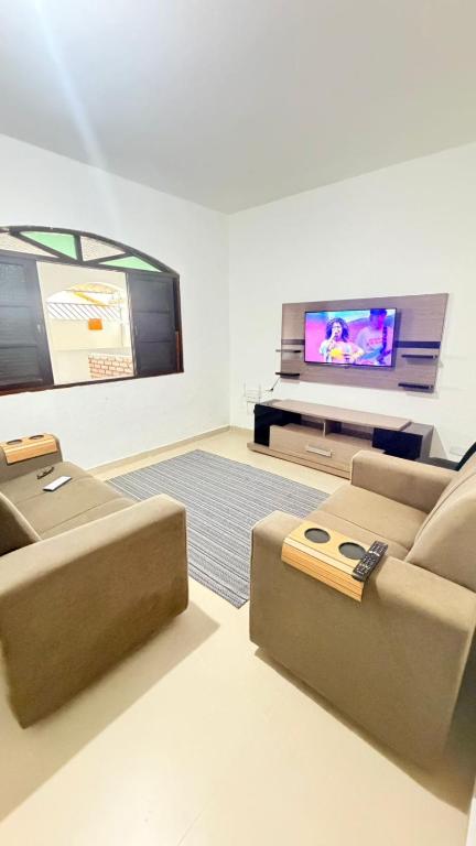 a living room with a couch and a flat screen tv at Casa para 9 pessoas a poucos passos do Santuário de Aparecida in Aparecida