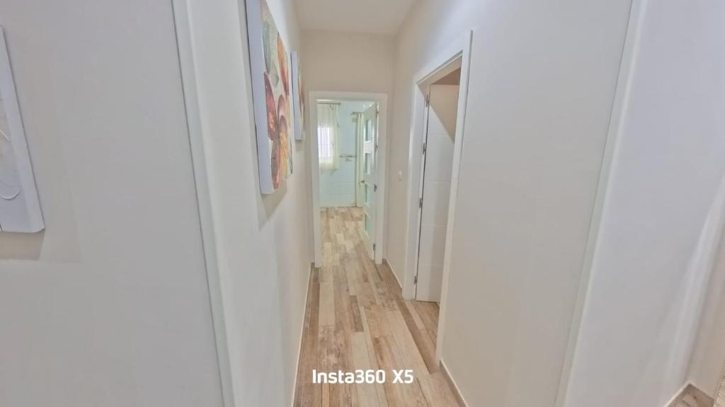 a hallway with white walls and a wooden floor at Apartamentos Bemar in Chipiona