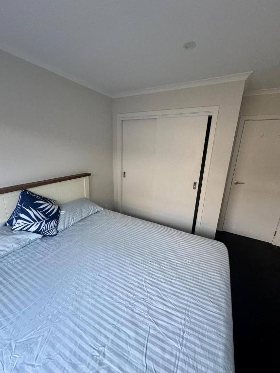 a bedroom with a bed with a blue pillow at Spacious One-Bedroom with Private Bathroom Aotea in Porirua
