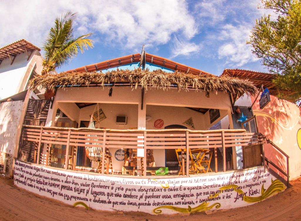 un bâtiment avec un toit de paille et un palmier dans l'établissement Trip Bar Hostel, à Jericoacoara
