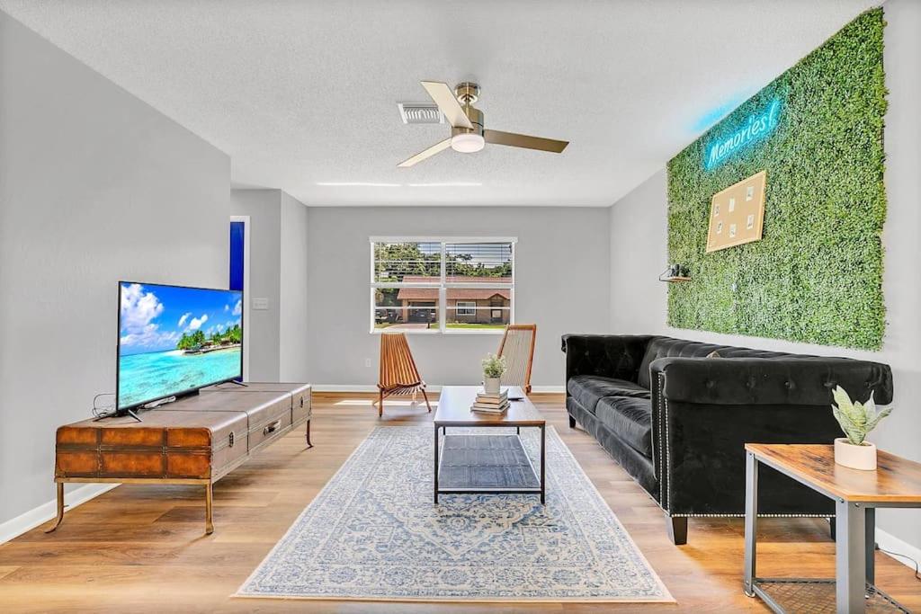 a living room with a black couch and a tv at Blue Spring Getaway with Fire Pit in Orange City