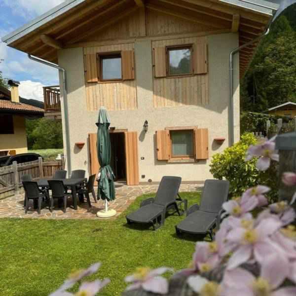 a yard with chairs and an umbrella and a house at Chalet in Pieve di Ledro-Ledrosee 57751 in Pieve Di Ledro
