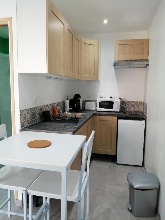 a kitchen with a white table and a white refrigerator at L'escale in Mers-les-Bains