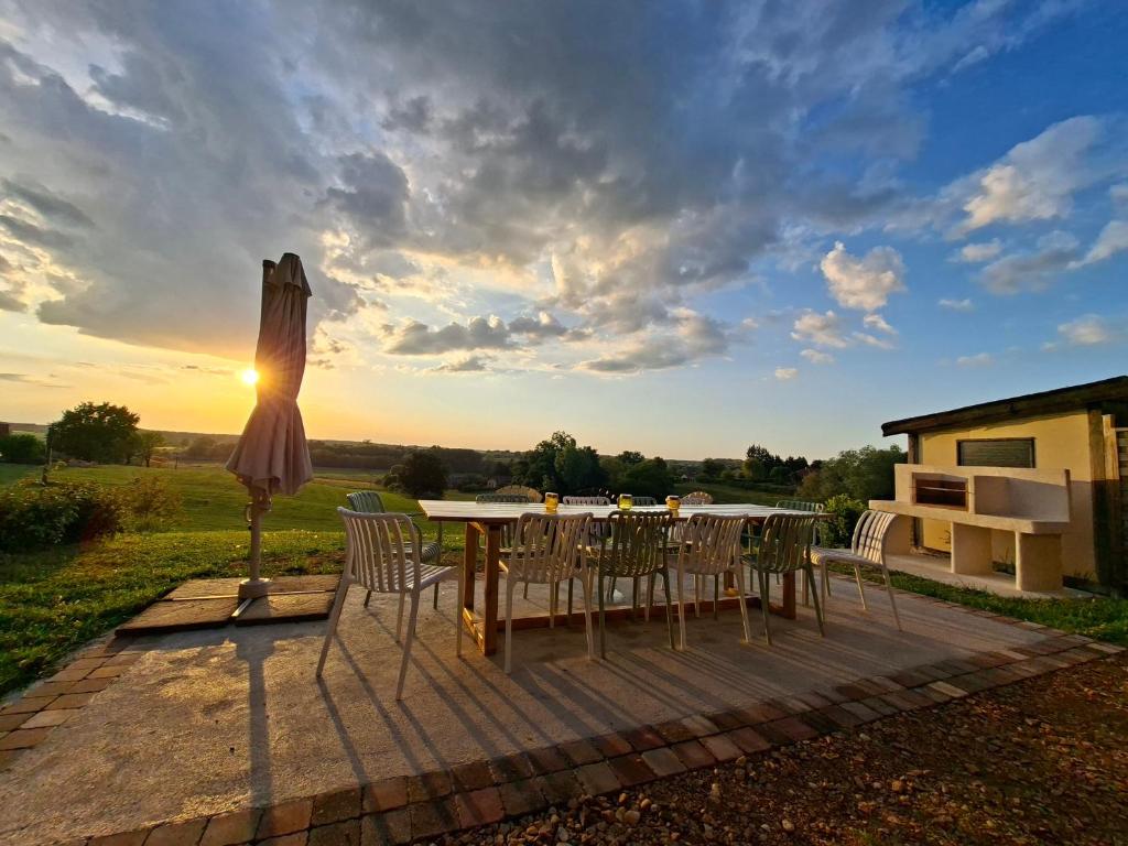 a patio with an umbrella and a table and chairs at Gîte familial 10 pers jardin et piscine in Saint-Amour