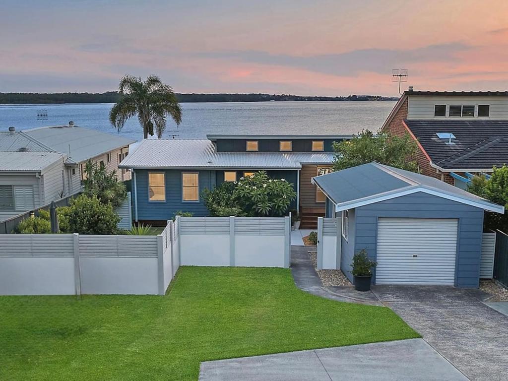 a house with a white fence in a yard at Scenic Shores in Budgewoi