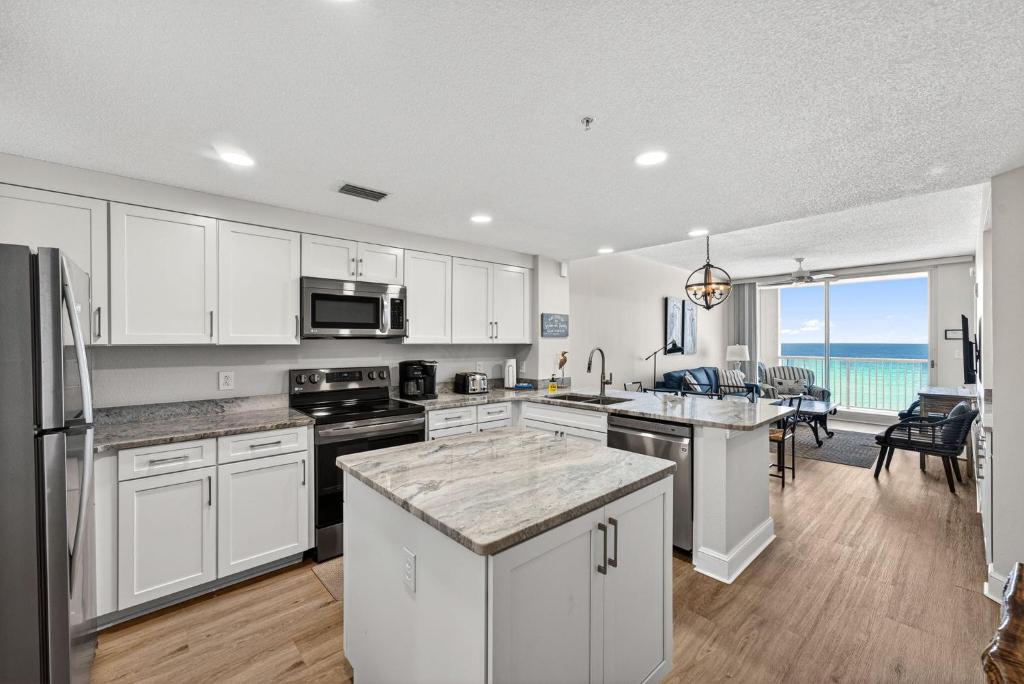 a kitchen with white cabinets and a view of the ocean at Majestic Resort! Newly Updated Beachfront 3BR Condo in Panama City Beach