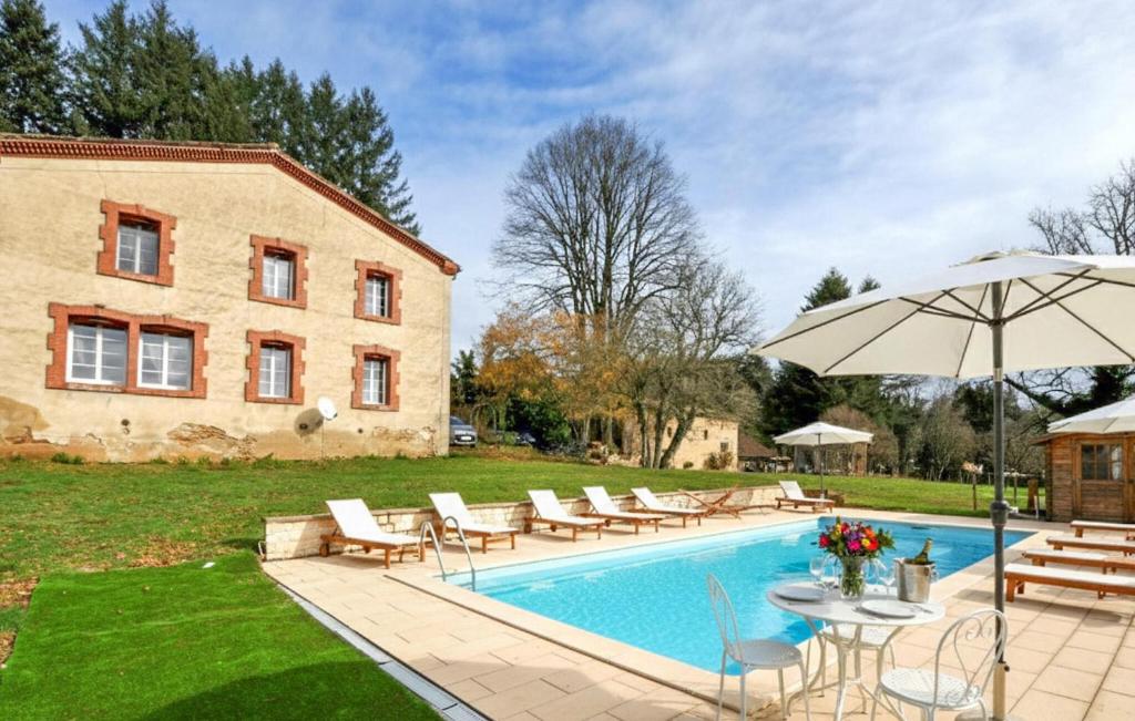 a pool with chairs and an umbrella next to a building at Authentique Maison Piscine in Saint-Amans-Valtoret