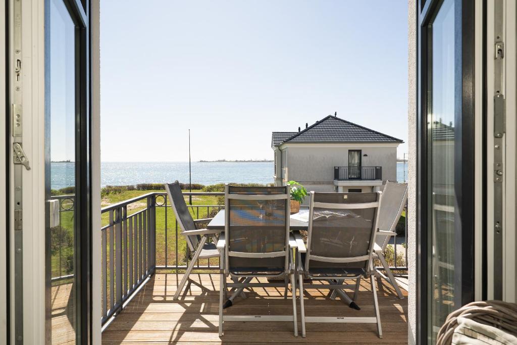 a balcony with a table and chairs and the ocean at Haus Vogelflug strandleev3 in Fehmarnsund