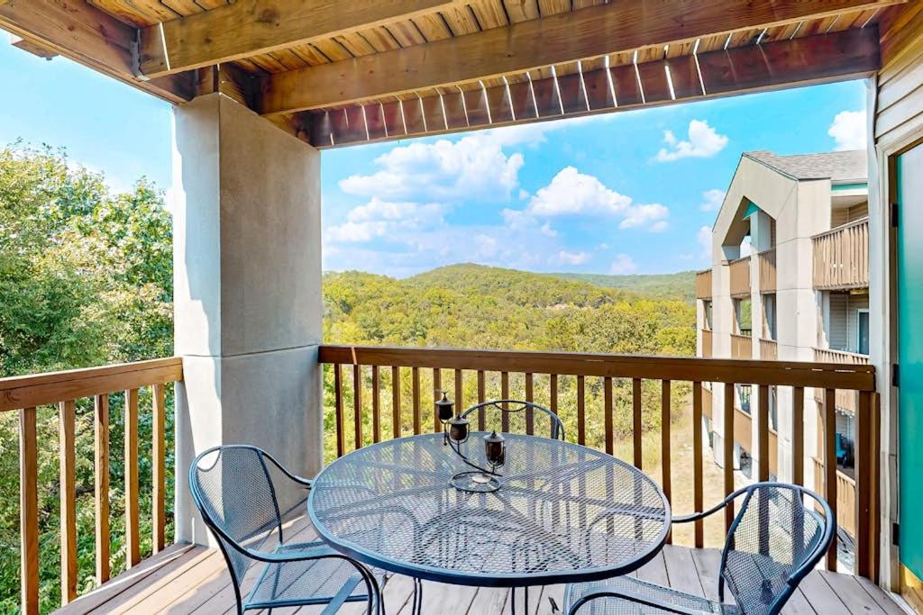 a patio with a table and chairs on a balcony at Treetop Tranquility in Branson