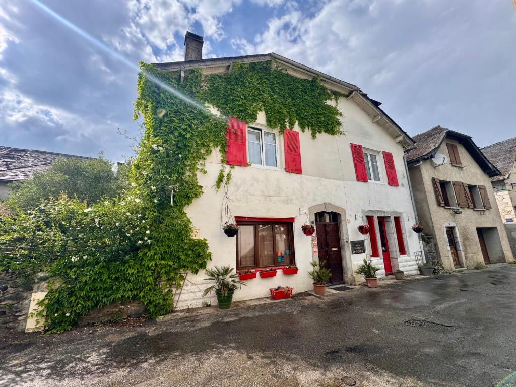a building with red shutters and ivy on it at Maison Luard in Bedous