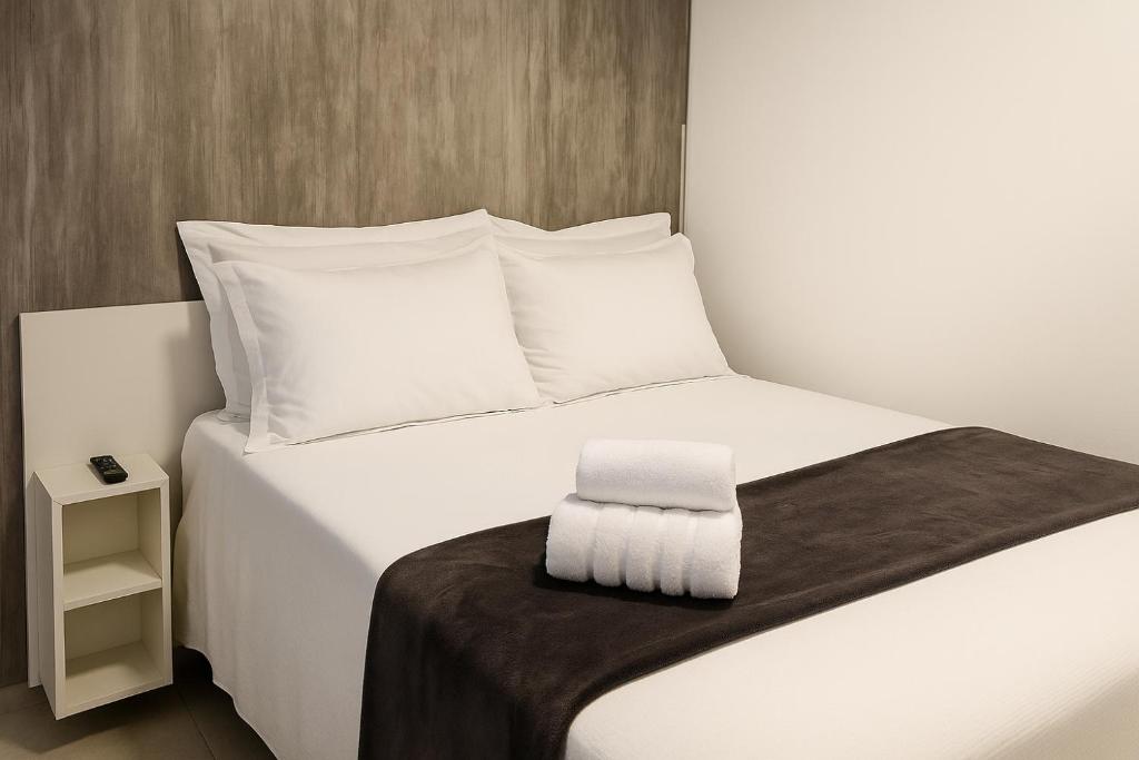 a bed with white sheets and a brown blanket at Loft Pelotas in Pelotas