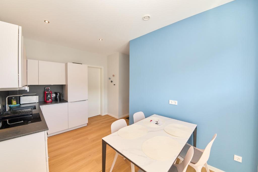 a kitchen and dining room with a white table and chairs at Burgblick Apartment Schieferblau in Bernkastel-Kues
