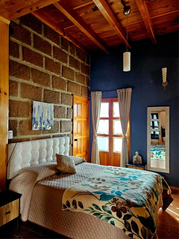 ein Schlafzimmer mit einem Bett vor einer Ziegelwand in der Unterkunft Wulkan Studio in Amecameca de Juárez
