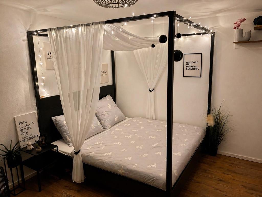 a bedroom with a canopy bed with white curtains at Studio Weidenkorb in Vaihingen an der Enz