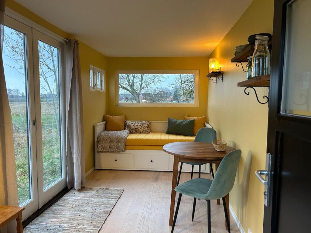 ein kleines Zimmer mit einer Bank, einem Tisch und einem Fenster in der Unterkunft Solvognen in Pejrup