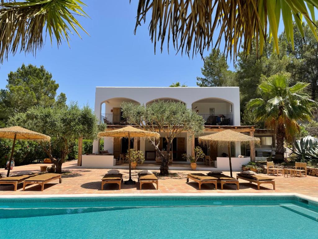 a resort with a swimming pool with chairs and umbrellas at Finca LA SELVA, Exclusive Villa in Benimussa in San Antonio