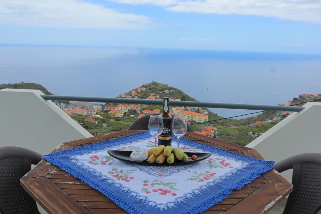 a table with a plate of fruit and a wine glass at Fifty`s House 1 By Sam Houses in Ribeira Brava