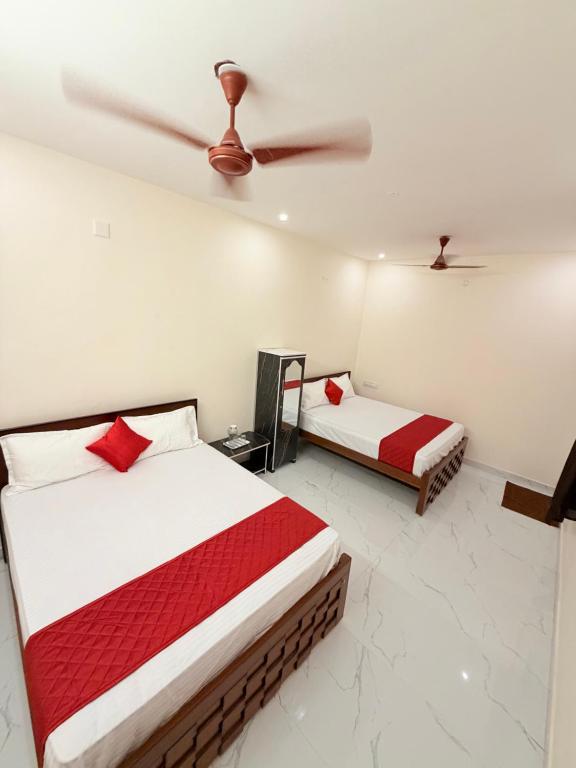 a bedroom with two beds and a ceiling fan at HARI HARA HOMEs in Rāmeswaram