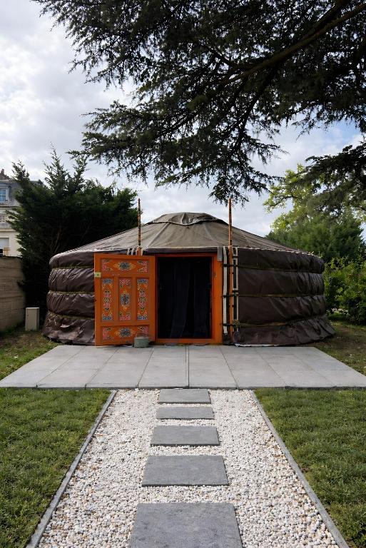 a yurt with an orange door in a yard at Yourte chaleureuse in Bois-le-Roi