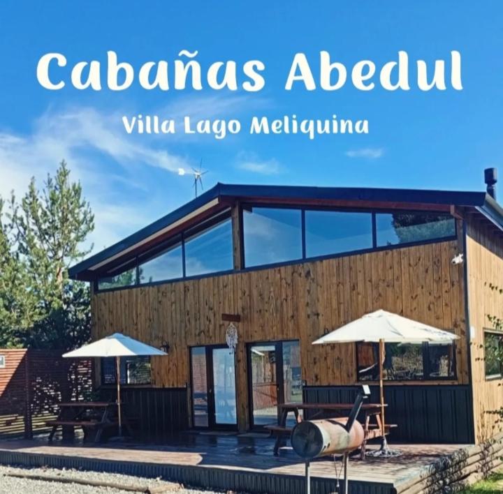 a building with two umbrellas in front of it at Cabañas Abedul in Lago Meliquina