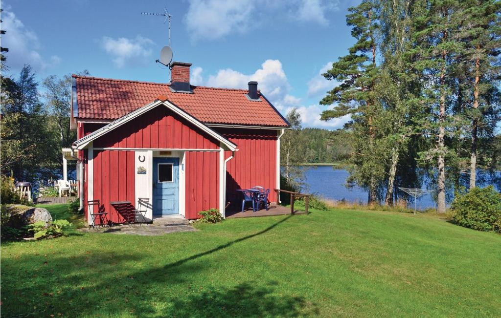 a red shed on a lawn next to a lake at 3 Bedroom Cozy Home In Åmål in Åmål