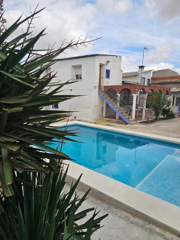 a blue swimming pool in front of a white building at El Patio de Doña Tere in Villarta de San Juan
