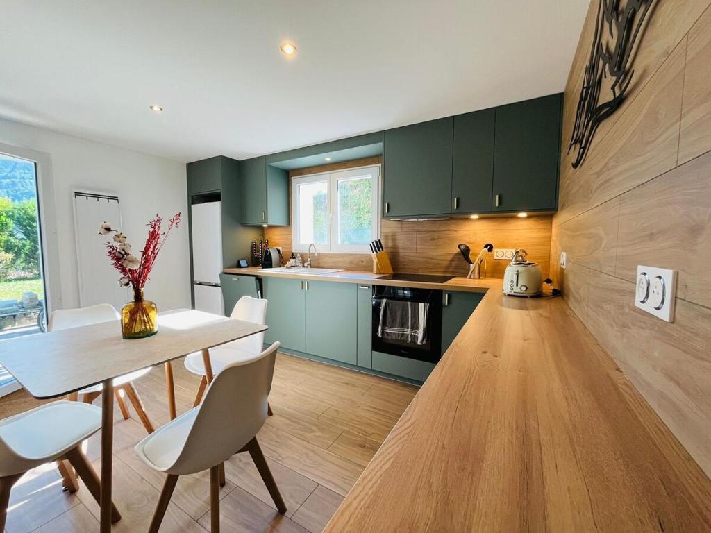a kitchen with green cabinets and a table and chairs at Modern haven with garden in Marignier