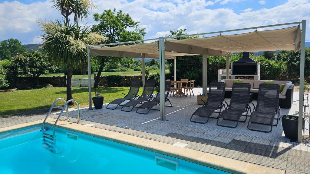a swimming pool with a pavilion and chairs next to a swimming pool at Campos Essencia in Arganil