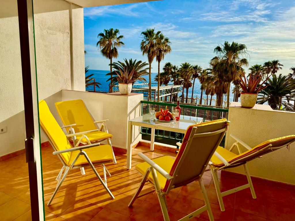 a balcony with chairs and a table with a view of the ocean at Esmeralda in Callao Salvaje