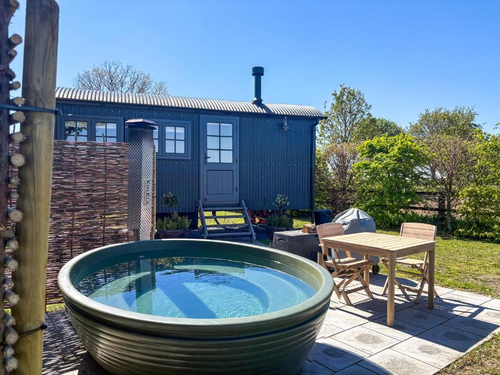 a large bath tub sitting on a patio with a table at Shepherds Hut - Uk49729 in King's Lynn