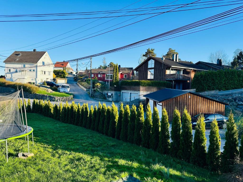 a row of trees in a yard with a house at Central leilighet i Kristiansand Vågsbygd in Kristiansand