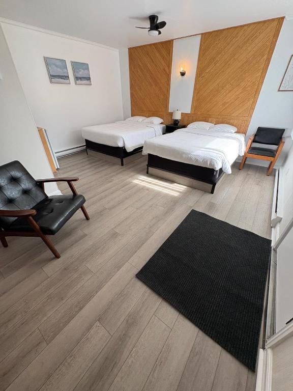 a hotel room with two beds and a chair at Le Délice Motel Restaurant in Mont-saint-pierre