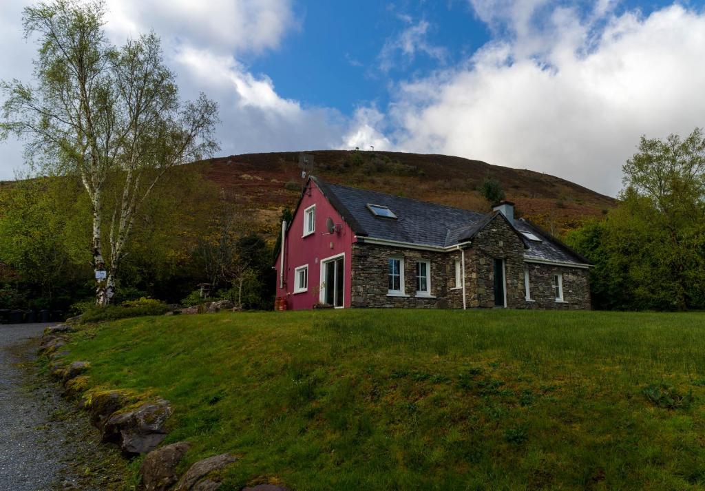 a red house on a green field with a hill at An Charraig in Killarney