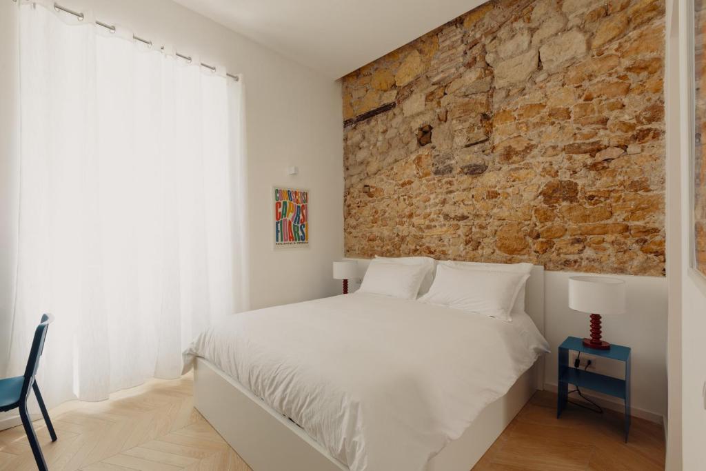 a bedroom with a white bed and a brick wall at Andrew suites in Nettuno