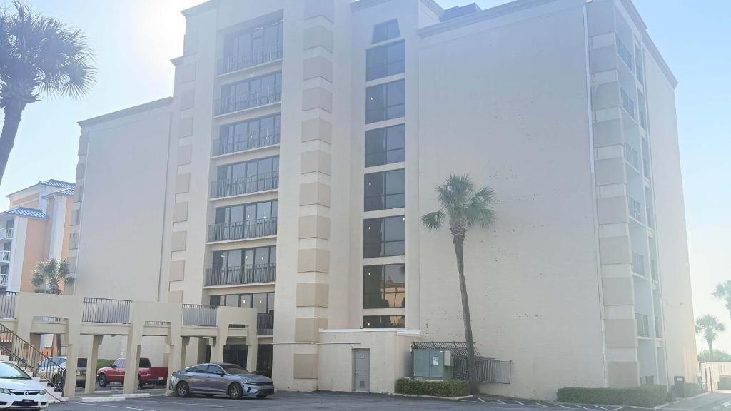 a large white building with palm trees in front of it at Atlantic Crest Inn and Suites in Myrtle Beach