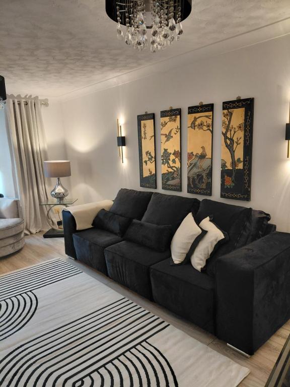 a living room with a black couch and a chandelier at Little Nuek in Largs