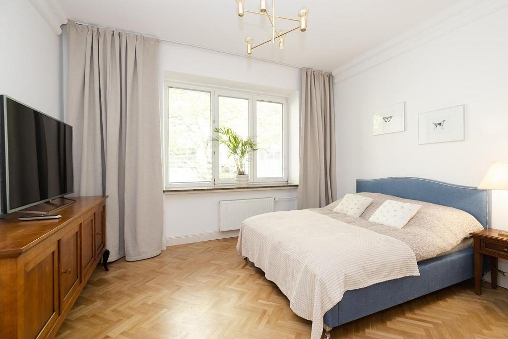 a bedroom with a bed and a flat screen tv at Sienna Central Studio & Parking in Warsaw