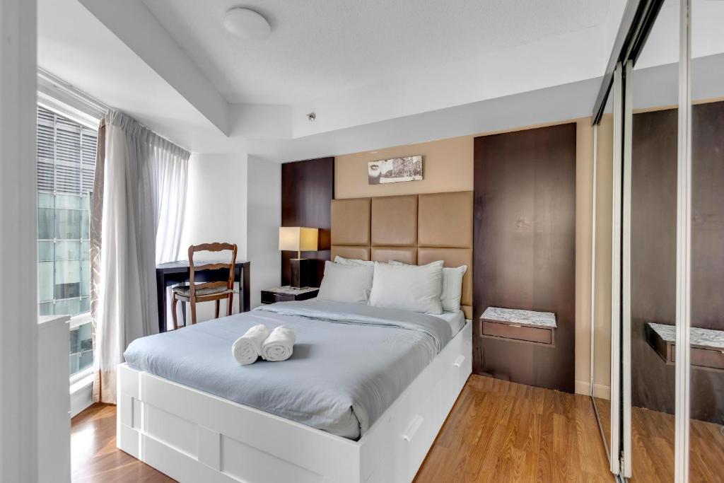 a bedroom with a large bed with two shoes on it at The Pantages Suites in Toronto
