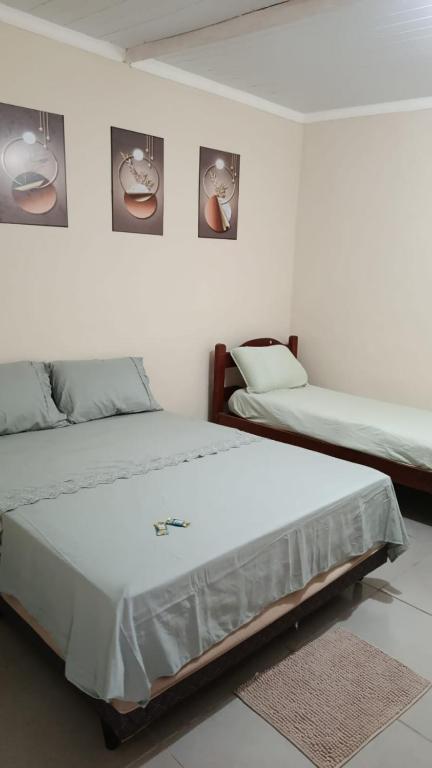 a bedroom with two beds and two pictures on the wall at hospedagem da rosa in Morretes