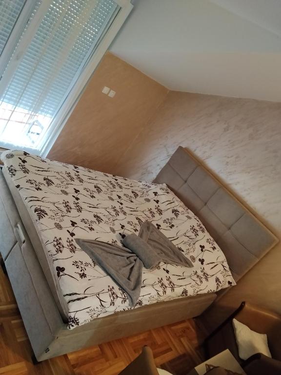 a small bed in a room with a window at Apartman Jaca in Požarevac