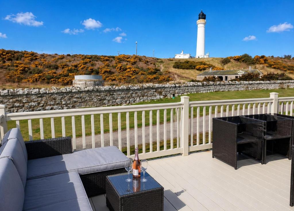 a patio with a couch and a lighthouse in the background at Aurora Beacon View in Lossiemouth