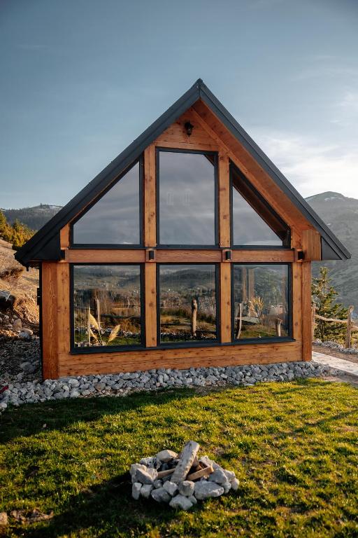 a house with a large window on top of a field at Mountain Dream Chalet Durmitor in Nedajno