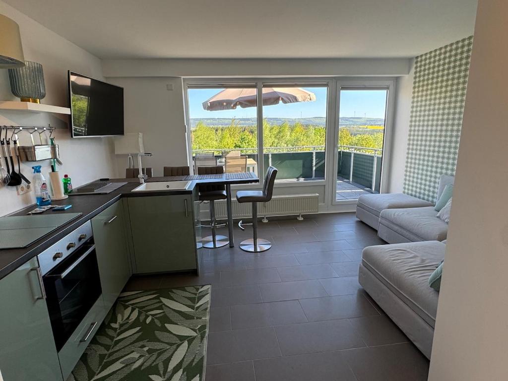 a kitchen and living room with a table and an umbrella at Traum Ferienwohnung Kell am See in Kell