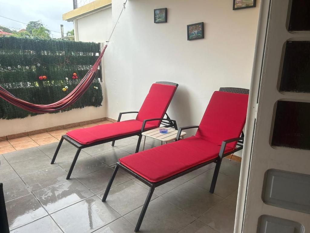 a pair of red chairs sitting on a porch at La maison de la plage in Sainte-Luce