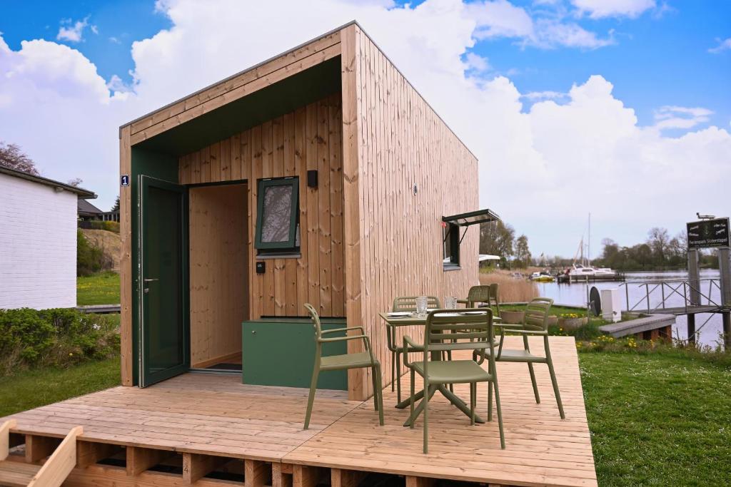 a tiny house with a table and chairs on a deck at Tiny House Nook 1 - Green&Tiny Hideaway Eider in Süderstapel
