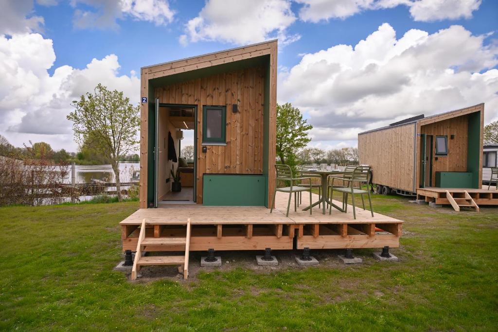 a small wooden cabin with a table and chairs at Tiny House Nook 2 - Green&Tiny Hideaway Eider in Süderstapel