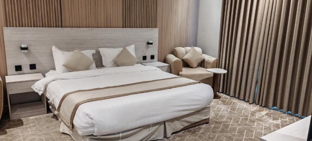 a bedroom with a large bed and a chair at السناء للشقق المخدومة Alsanaa in Jeddah
