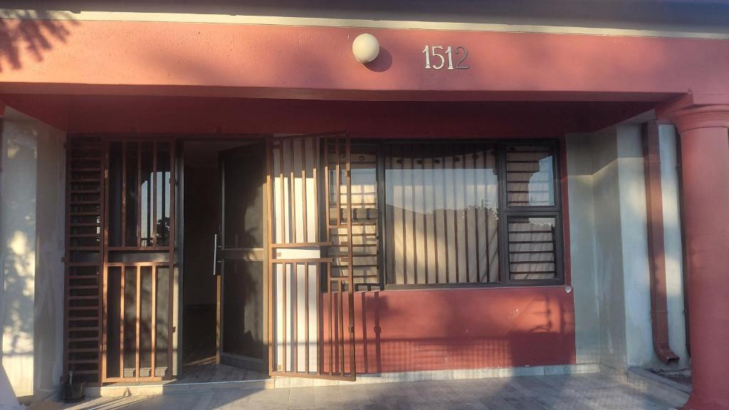 a front door of a pink building with a gate at Hyponia 1512 in Oshikuku