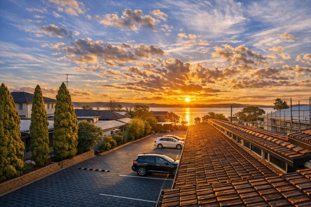 a sunset over a parking lot with cars parked at Jetty Motel The Entrance in The Entrance