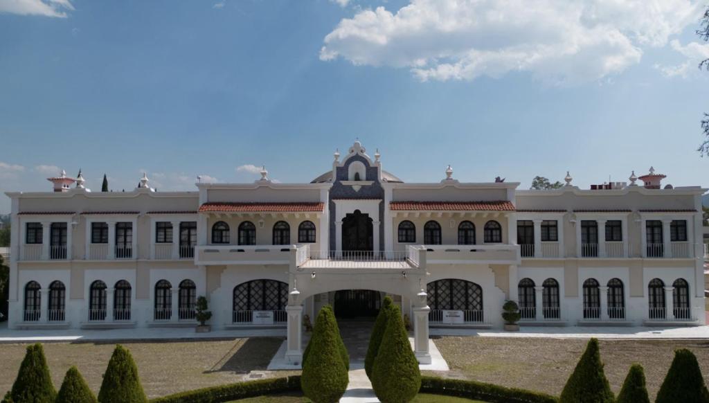 a large white building with trees in front of it at Hotel Royal Spa in Zimapán